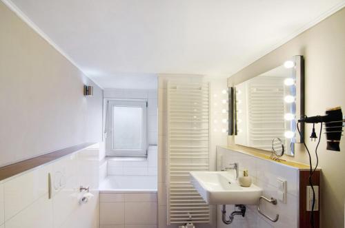 a white bathroom with a sink and a mirror at De Lüttje Utkiek in Bühren
