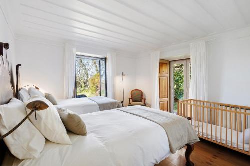 a white bedroom with two beds and a crib at Casa Do Alto Da Coutada in Ponte de Lima