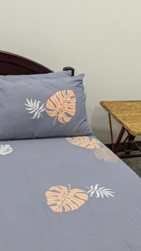 a bed with a blue blanket with flowers on it at KATHIR Guest House in Jaffna
