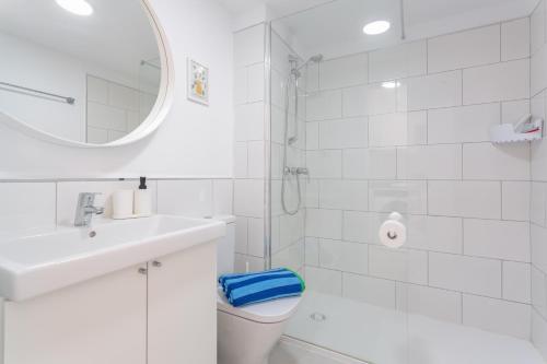 a white bathroom with a toilet and a sink at Coco Canaria in Corralejo