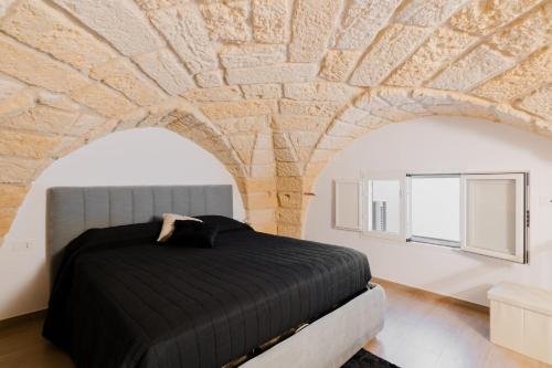 a bedroom with a bed and a stone wall at Casa Ninì in Galatone