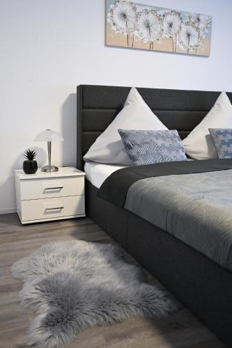 a bedroom with a bed and a nightstand with a white drawer at Timos Ferienwohnung in Schmallenberg
