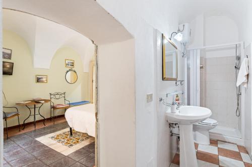 a white bathroom with a sink and a toilet at Romeo e Giulietta Rooms in Bosa