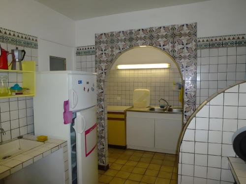 a kitchen with an archway and a white refrigerator at Gîte Paysan La Grange in Montrond