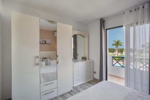 a white bedroom with a bed and a mirror at Great Bungalow Maspalomas in Maspalomas