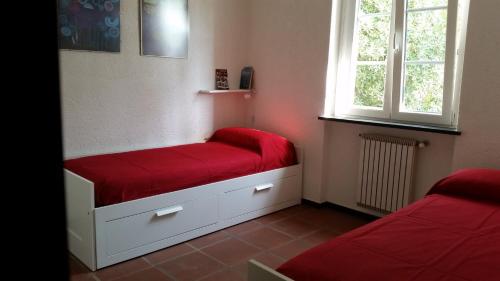 フィナーレ・リーグレにあるCollina e Mareの赤いシーツと窓が備わるベッド2台付きの客室です。