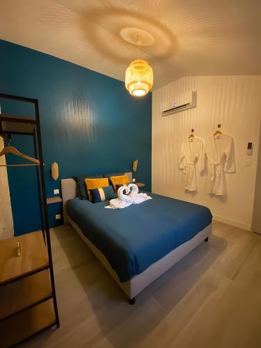 a blue bedroom with a bed with a blue wall at La Folie Romantique, Avec Spa in Sublaines
