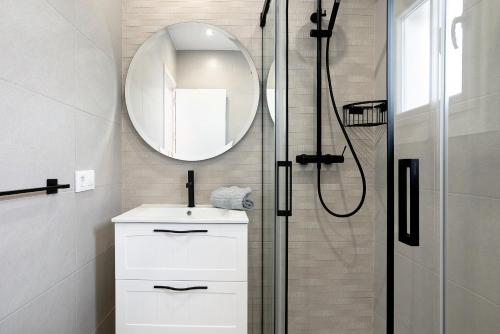 a bathroom with a sink and a shower with a mirror at Chalet Fuente3 piscina común famila in Conil de la Frontera