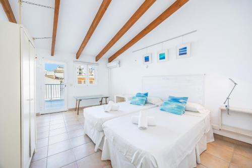 two beds in a room with white walls and wooden ceilings at Cal Rei in Inca