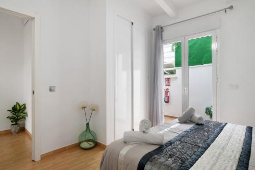 a white bedroom with a bed and a window at Villa Españolillas in Olvera