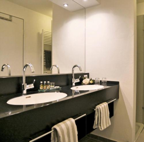 a bathroom with two sinks and two mirrors at Ferienhaus Jümmers - Pidder in Horumersiel