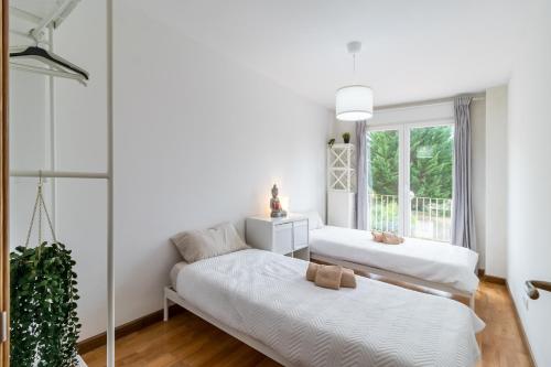 two beds in a white room with a window at Surf House Gama in Gama