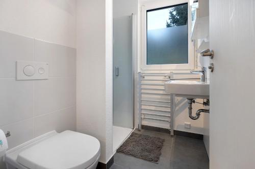 a bathroom with a toilet and a sink and a window at Unterkunft für Messen und Freizeit in Hemmingen