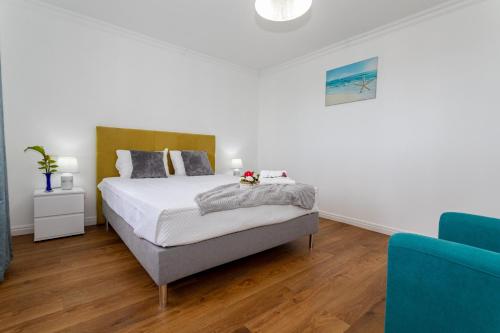 a white bedroom with a bed and a blue couch at Oásis Fonte Grande in Santo António