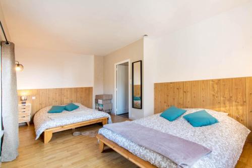 a bedroom with two beds with blue pillows at La ferme du château in Venon