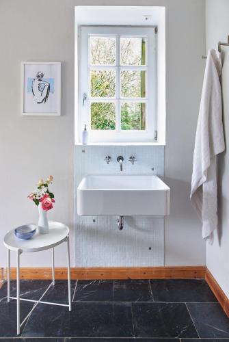 a white bathroom with a sink and a window at Künstlerwohnung im Naturpark in Meezen