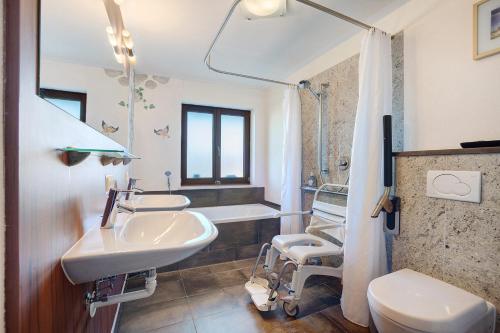a bathroom with two sinks and a toilet and a tub at Freiraum in Weiler-Simmerberg