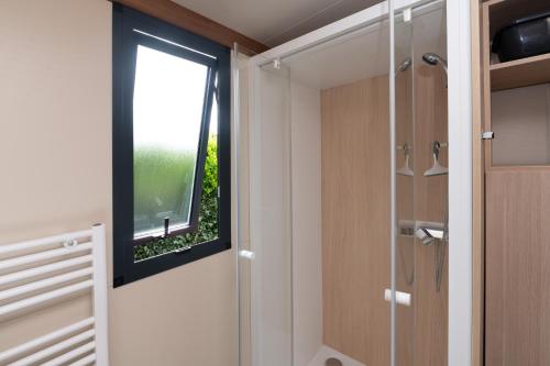 a bathroom with a window and a walk in shower at Chalet 20m2 - Ile Vierge in Plouhinec