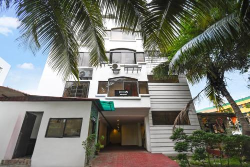 a white building with a palm tree in front of it at Hotel O New Alipore in Kolkata