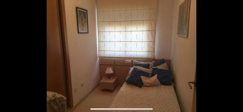 a small room with a bed with blue pillows at Escapada Ideal en Oropesa in El Borseral