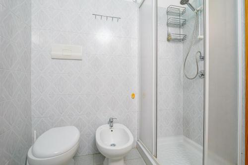 a white bathroom with a toilet and a shower at Quadrilocale Le Colonne in Lu Lioni