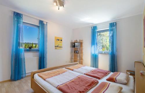 a bedroom with a bed and two windows with blue curtains at Ferienwohnung Walter in Ellenbach