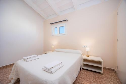 a white bedroom with a white bed and a window at Can Claret in Felanitx