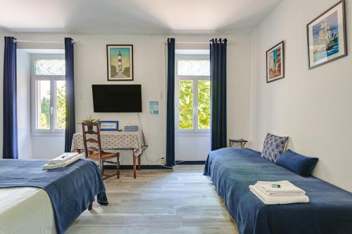 a room with two beds and a desk and a tv at Chambre d'hote Saphir in Genouillé