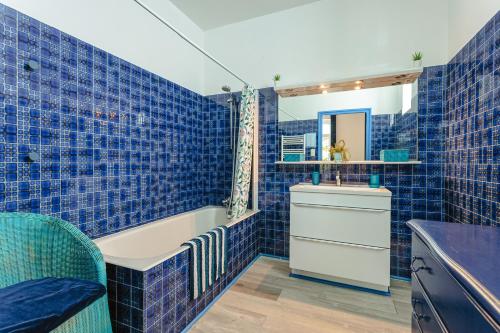 a blue tiled bathroom with a tub and a sink at Chambre d'hote Saphir in Genouillé