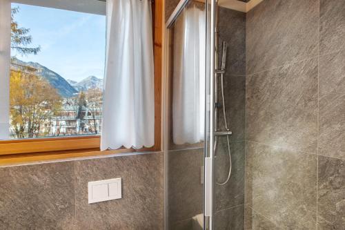 a shower with a glass door and a window at Quattropassi Bormio Mortirolo in Bormio
