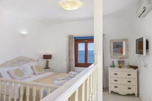 a white bedroom with a bed and a staircase at Caldera Studios in Astypalaia