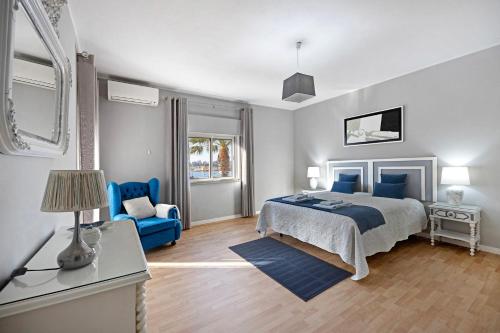 a bedroom with a bed and a blue chair at Casa Vista Rio in Ferragudo
