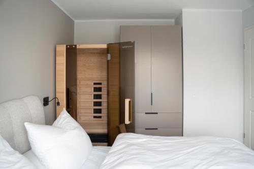 a bedroom with a white bed and a closet at Flutgold Dangast in Dangast