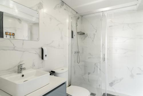 a white bathroom with a sink and a shower at Porto Nova Vivenda em Lever in Lever