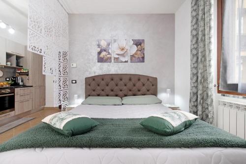 a bedroom with a large bed with two green pillows at Vigilio house in Calco