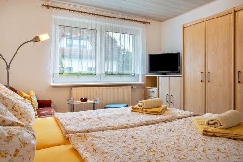 a bedroom with two beds and a tv and a window at Prerow Am Deich - Ferienwohnung 2 in Prerow