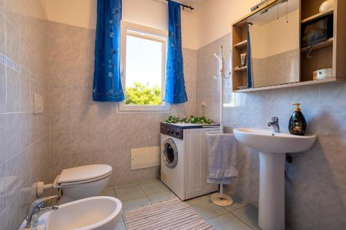 a bathroom with a toilet sink and a washing machine at Gadem House in Alghero