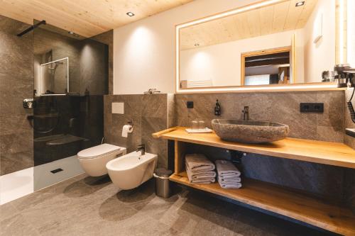 a bathroom with a sink and a toilet and a mirror at Egorta - Egarterhof Sexten in Sesto