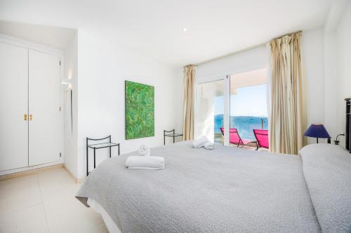 a white bedroom with a bed and a large window at Catalina 2b tres dormitorios in Port de Pollensa