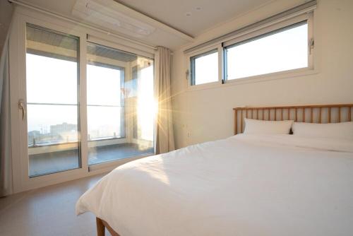 a bedroom with a white bed and two windows at 포항 이가리 독채 풀빌라 엘리시안 풀빌라펜션 in Pohang