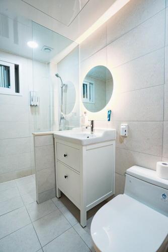 a bathroom with a toilet and a sink and a mirror at 포항 이가리 독채 풀빌라 엘리시안 풀빌라펜션 in Pohang