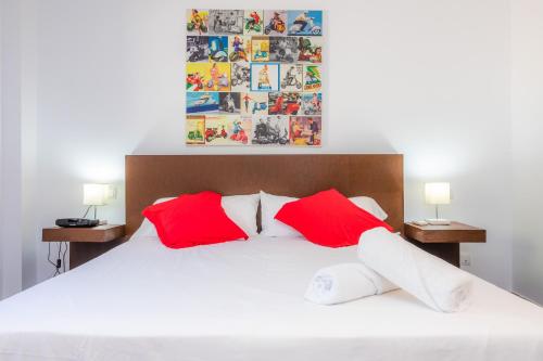 a bedroom with a white bed with red pillows at Finca Bionic in Artá