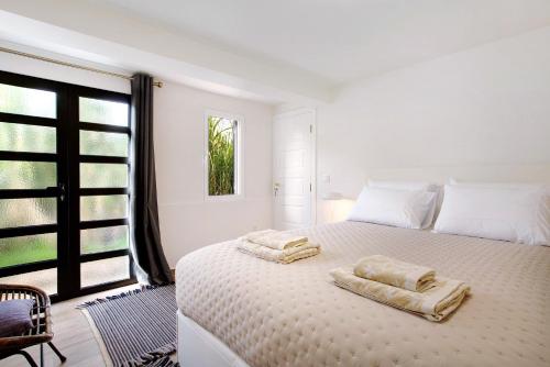 a white bedroom with two towels on a bed at Casa Do Lenhador in Canhas