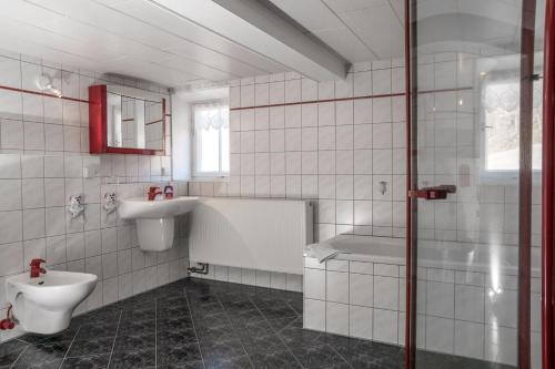 a white tiled bathroom with a sink and a toilet at Ferienwohnung Am Heideborn in Großschönau