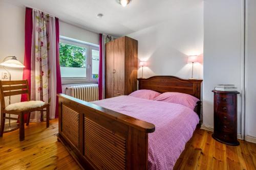 a bedroom with a bed and a chair and a window at Ferienwohnung Halunder in Leck