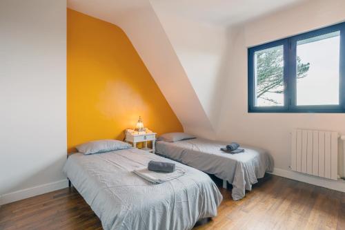 トレガンにあるMaison 100m de la plageの黄色い壁の部屋にベッドが2つある