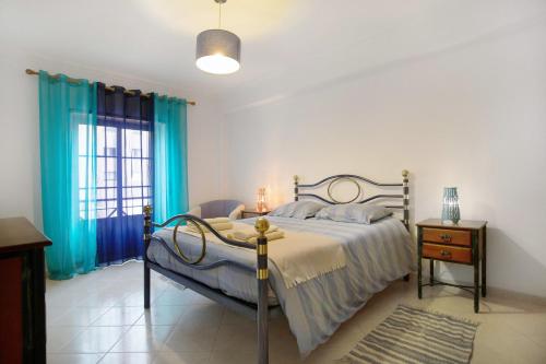 a bedroom with a bed and a window with blue curtains at A O - La Source in Peniche