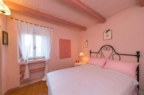 a bedroom with a bed with pink walls and a window at Casina nel Borgo Antico in Bibbona