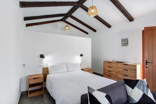a bedroom with a large white bed and wooden ceilings at Casa Celestina in Temisas