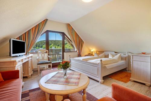 a bedroom with a bed and a tv and a table at Pension Bergblick in Marienberg